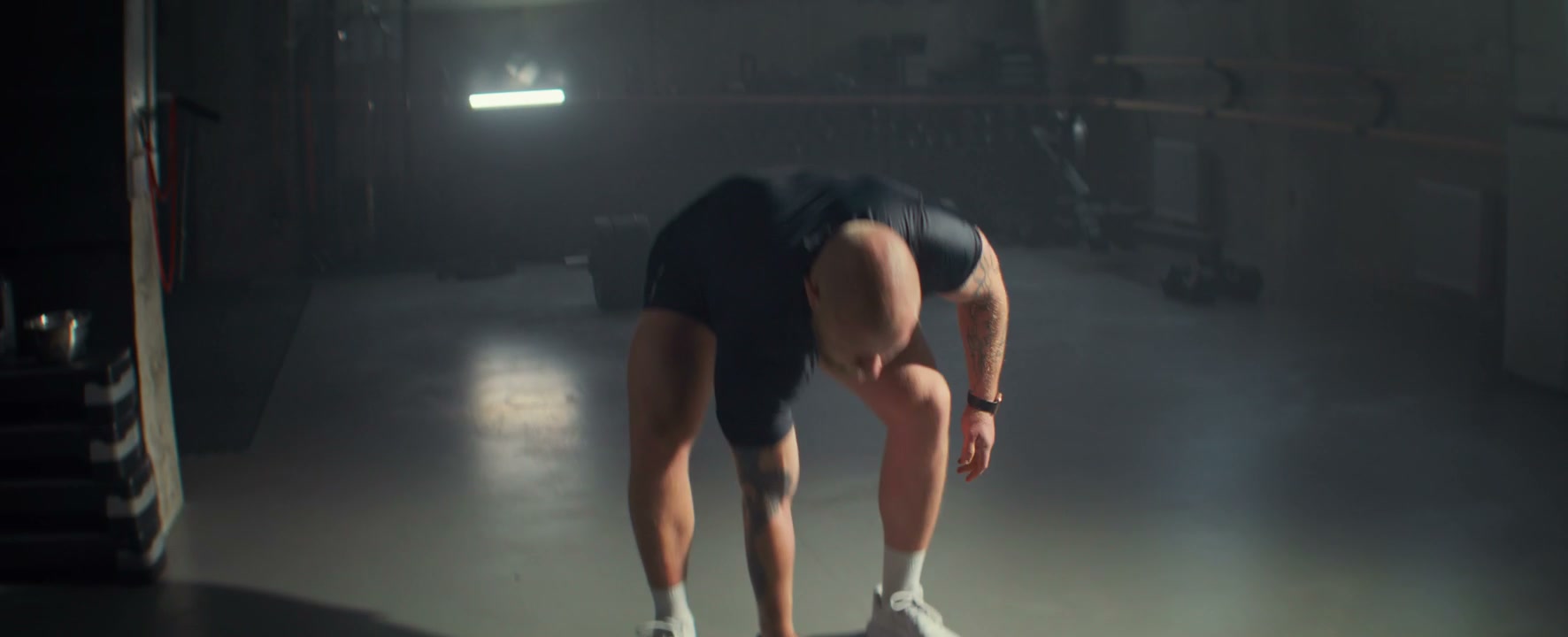 Man Performs Single Arm Dumbbell Press in Gym