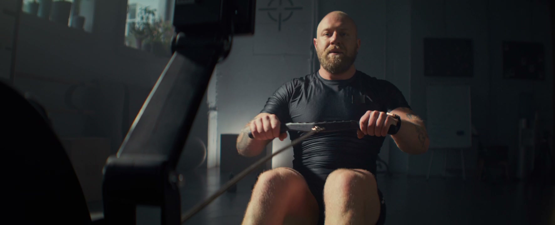 Man Training on a Rowing Machine in Gym