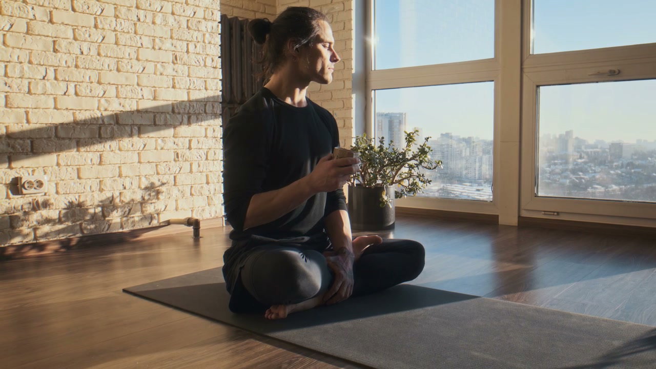 Man Relaxing in Yoga Studio with City View