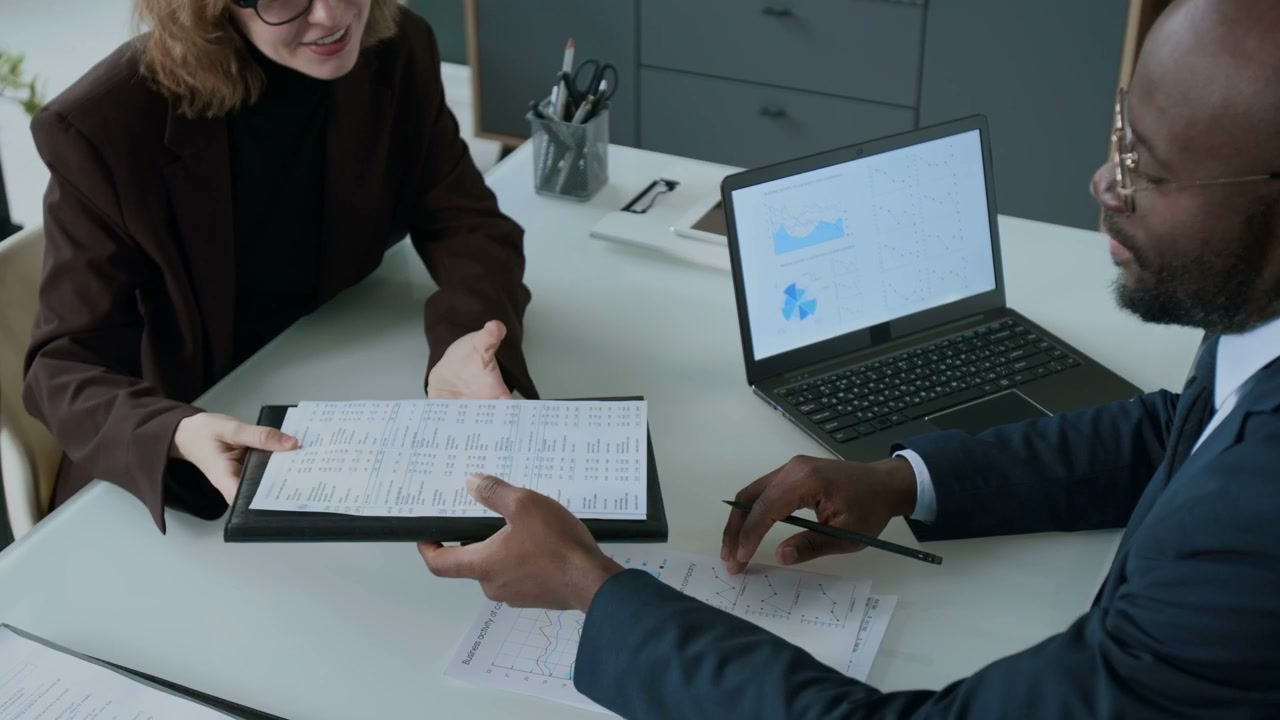 Business People Shaking Hands and Reviewing Documents
