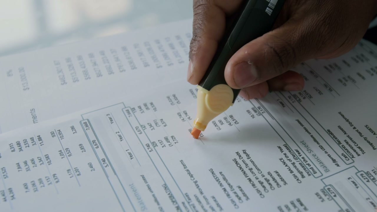 Close-Up of Hand Highlighting Financial Report