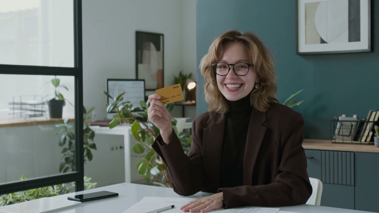 Happy Young Woman Holding Credit Card in Office