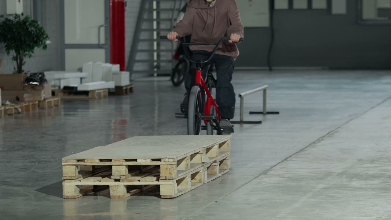 BMX Rider Performing Stunt on Pallets in Hangar
