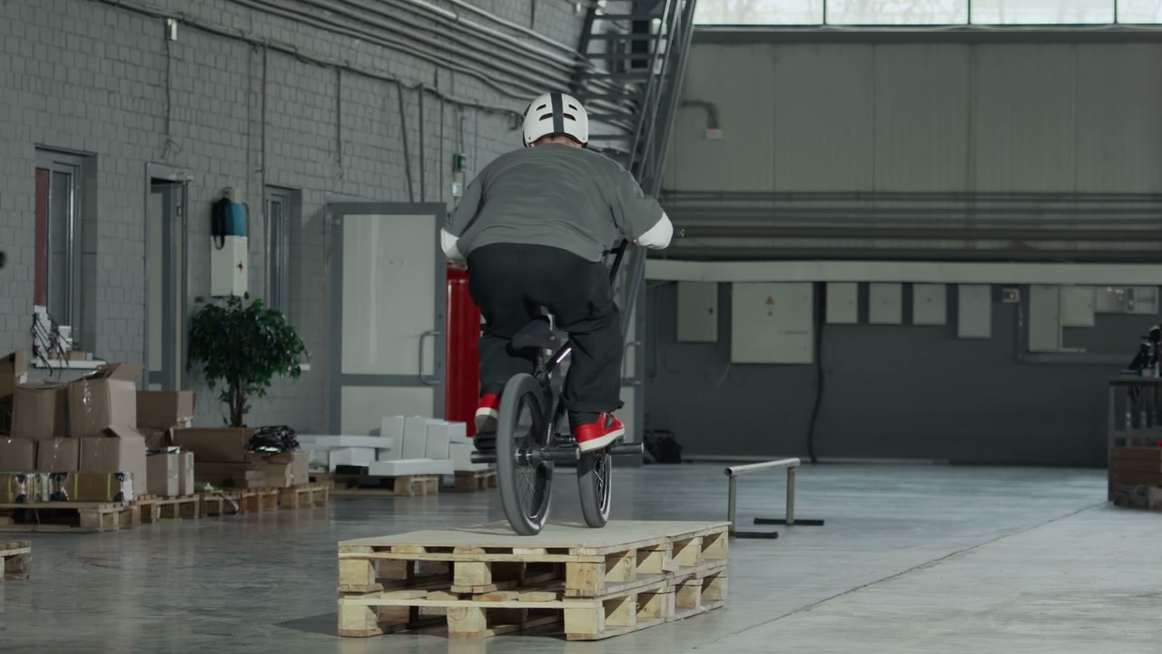 Two BMX Riders Performing Stunts in Hangar