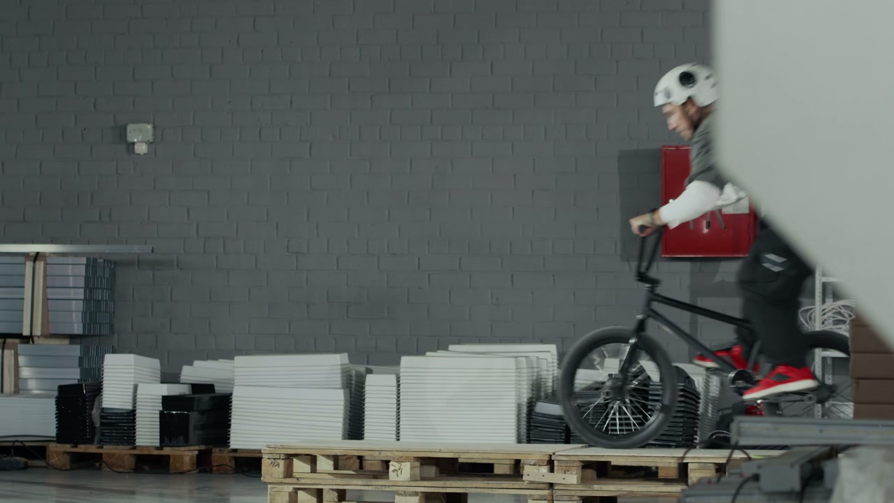 BMX Rider Jumps Over Pallets in Hangar