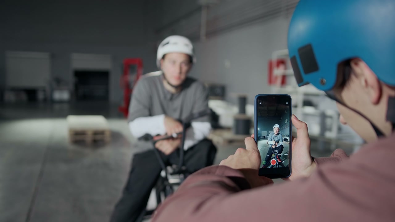 Vlogger Filming BMX Rider in Hangar