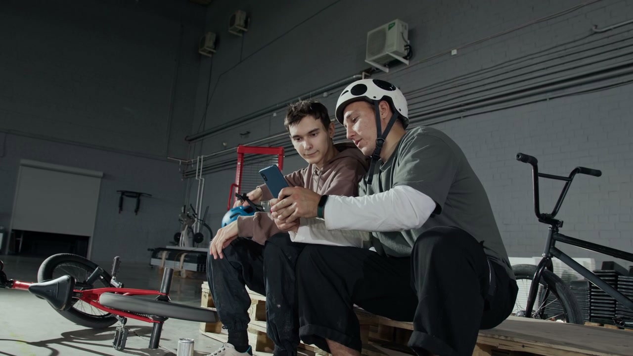 BMX Riders Using Smartphone in Hangar