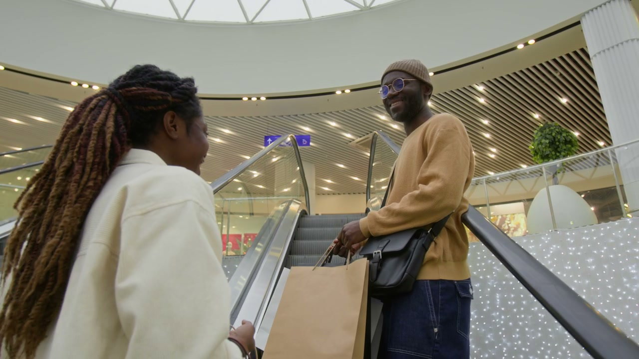 Couple Talking on Escalator with Shopping Bags