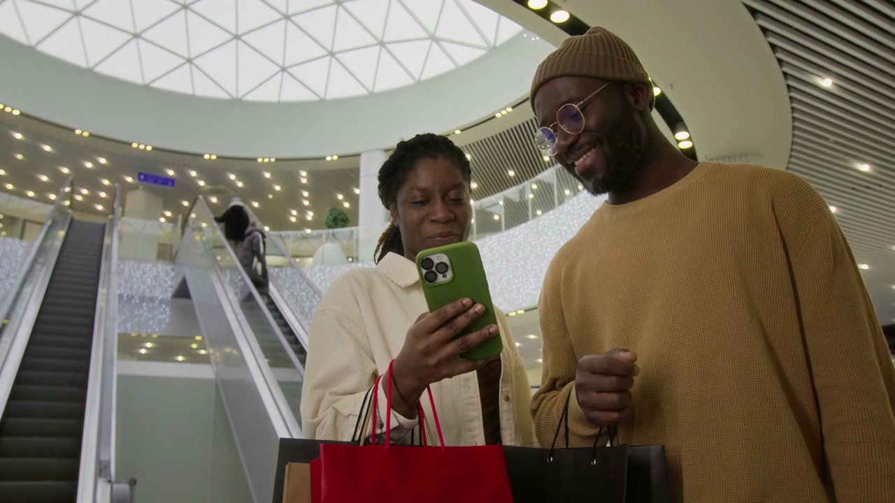 Happy Couple Browsing Phone in Shopping Mall