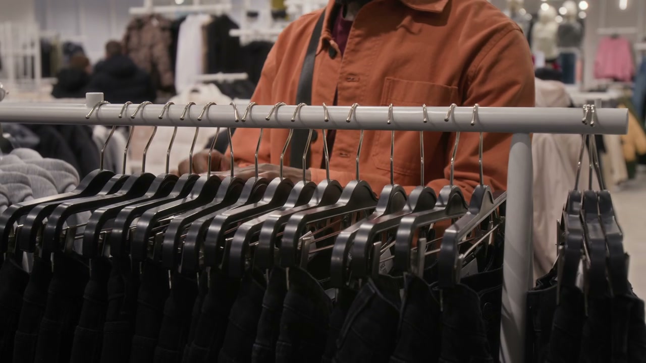 Man Browsing Clothes on a Rack