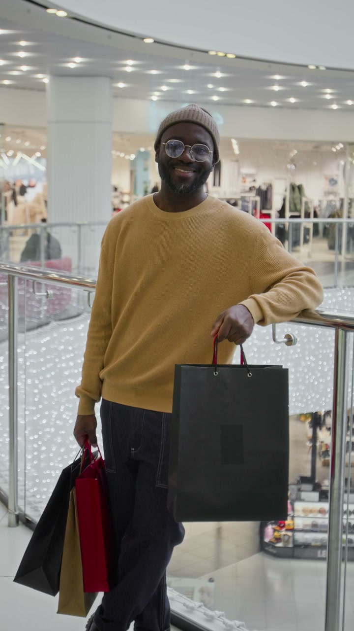Smiling Man with Shopping Bags in Mall