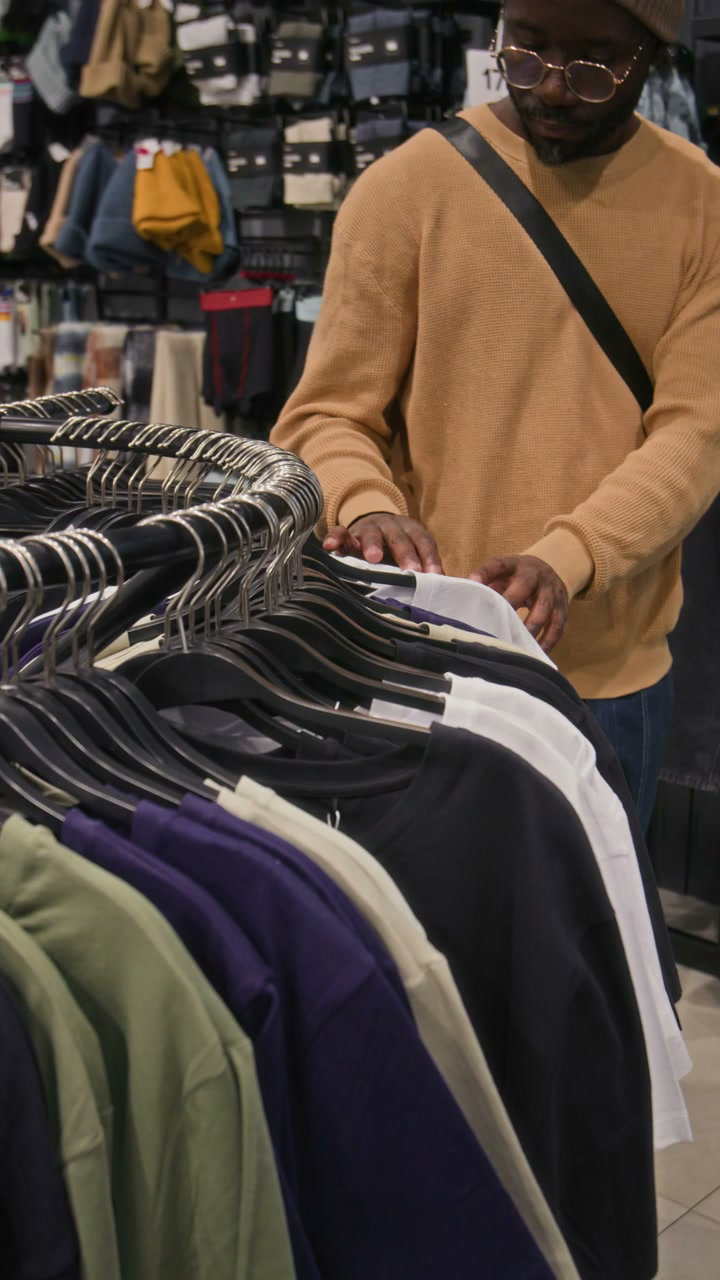 Man Browsing T-Shirts in Clothing Store
