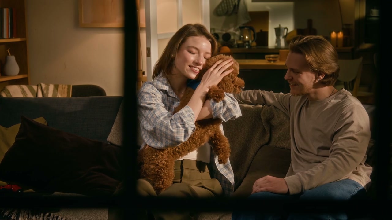 Cozy Couple Cuddling Poodle Dog on Sofa