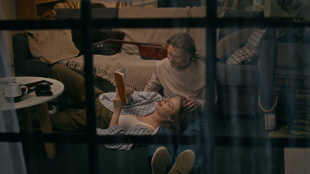 Couple Relaxing at Home Viewed Through Window