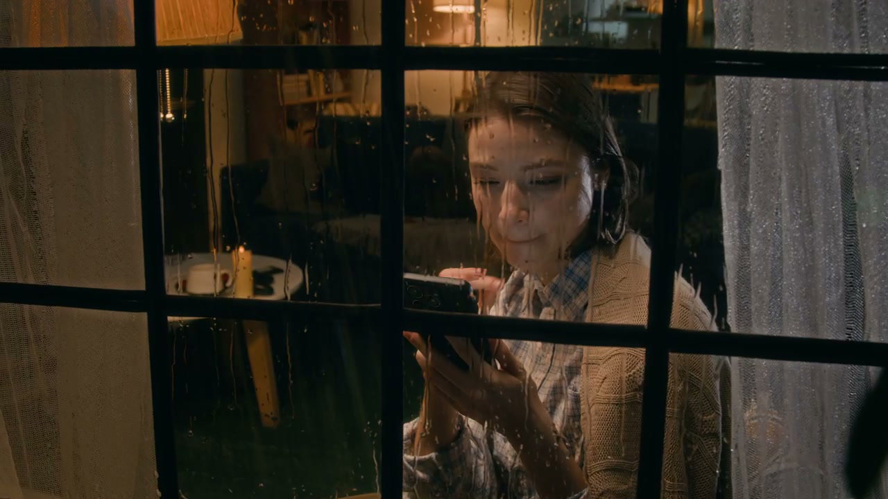 Happy Woman Using Phone by Rainy Window at Night