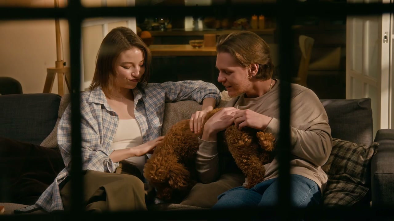 Couple Petting Dog on Sofa Through Window