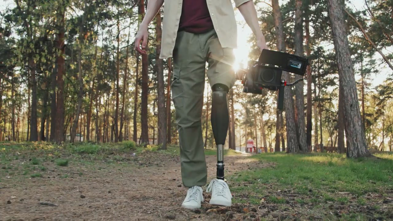 Cameraman with Prosthetic Leg Walking in Forest