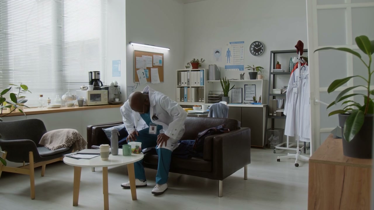 Tired Doctor Sits on Couch in Break Room