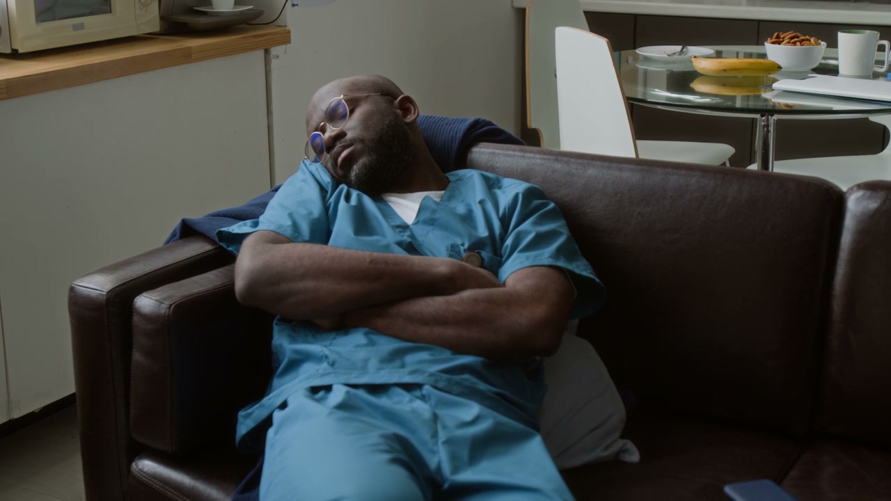 Doctor Asleep on Sofa in Break Room