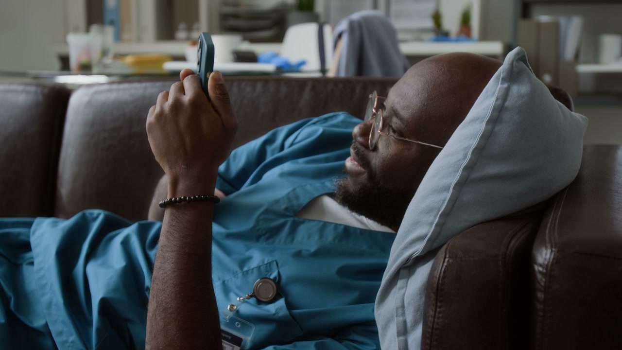 Doctor Resting on Sofa with Smartphone