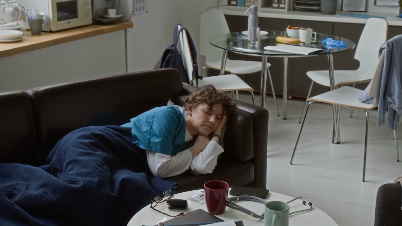 Doctor Napping on Sofa in Hospital Break Room