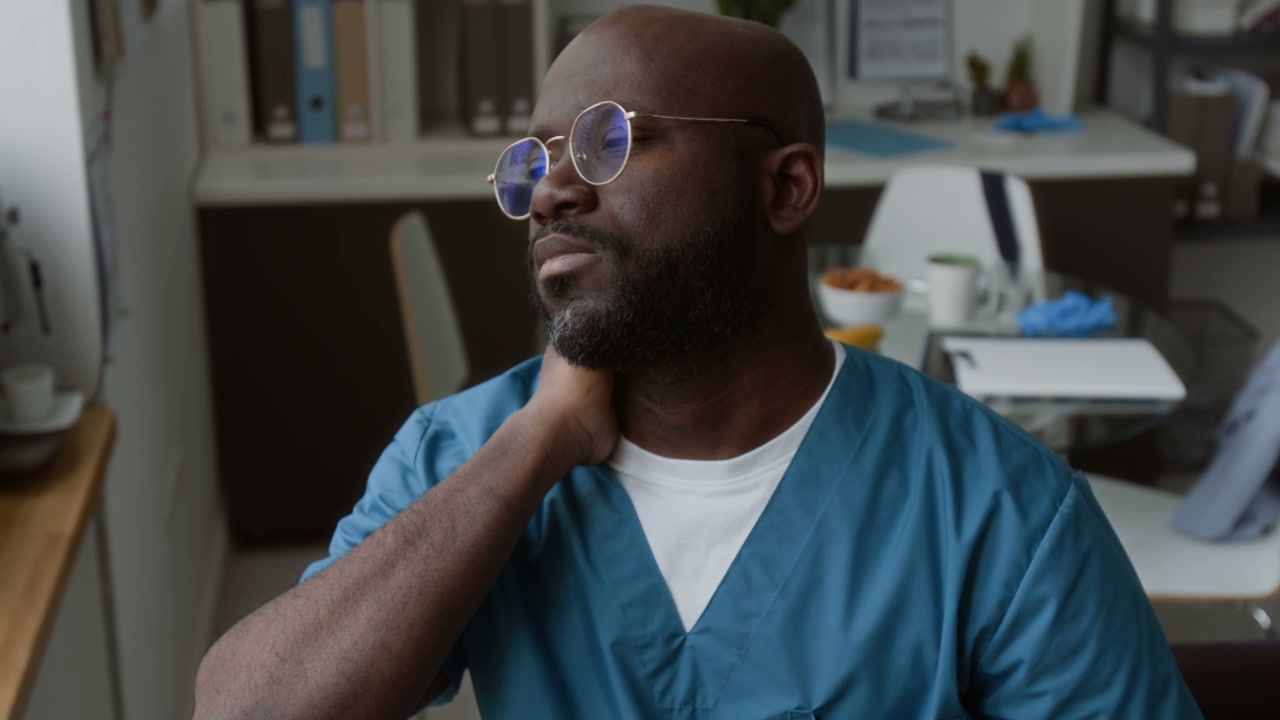 Male Doctor Stretching Neck in Break Room