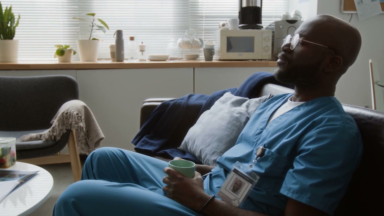 Tired Doctor Rests and Drinks Coffee in Break Room