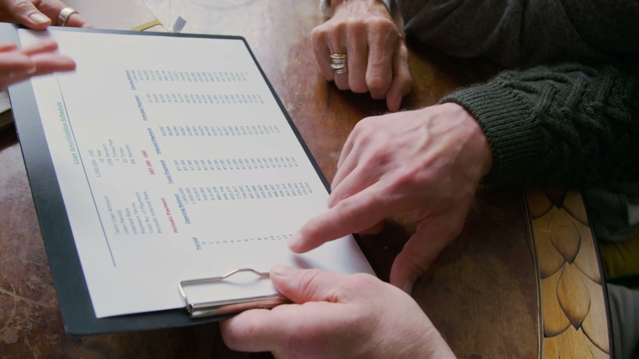 Hands Discussing Loan Amortization Schedule