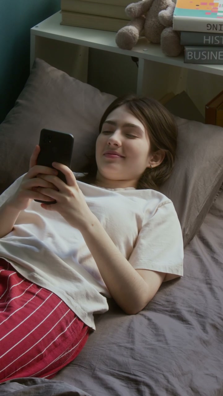 Young Woman Using Smartphone in Bed