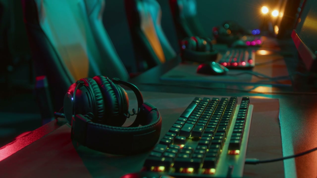 Headset Next to Keyboard and Computer Mouse at Gamers Desk in Cyberclub