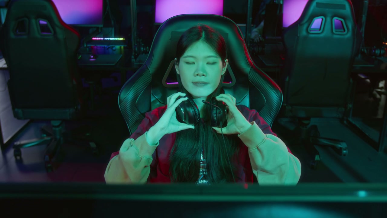 Portrait of Smiling Chinese Female Gamer Sitting at Computer in Cyberclub