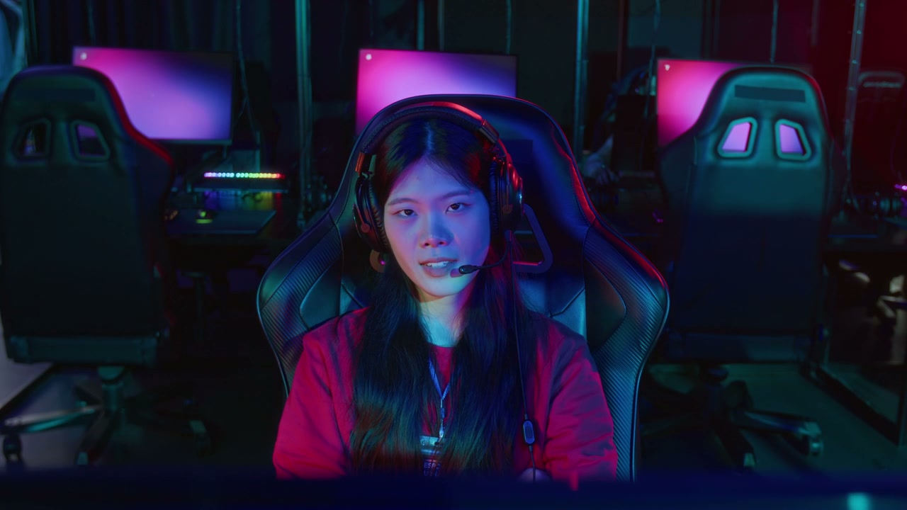 Portrait of Confident Asian Girl Gamer Sitting at Computer in Internet Club