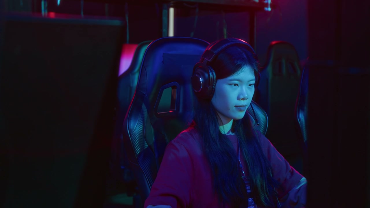 Focused Chinese Girl Playing Video Game in Internet Club