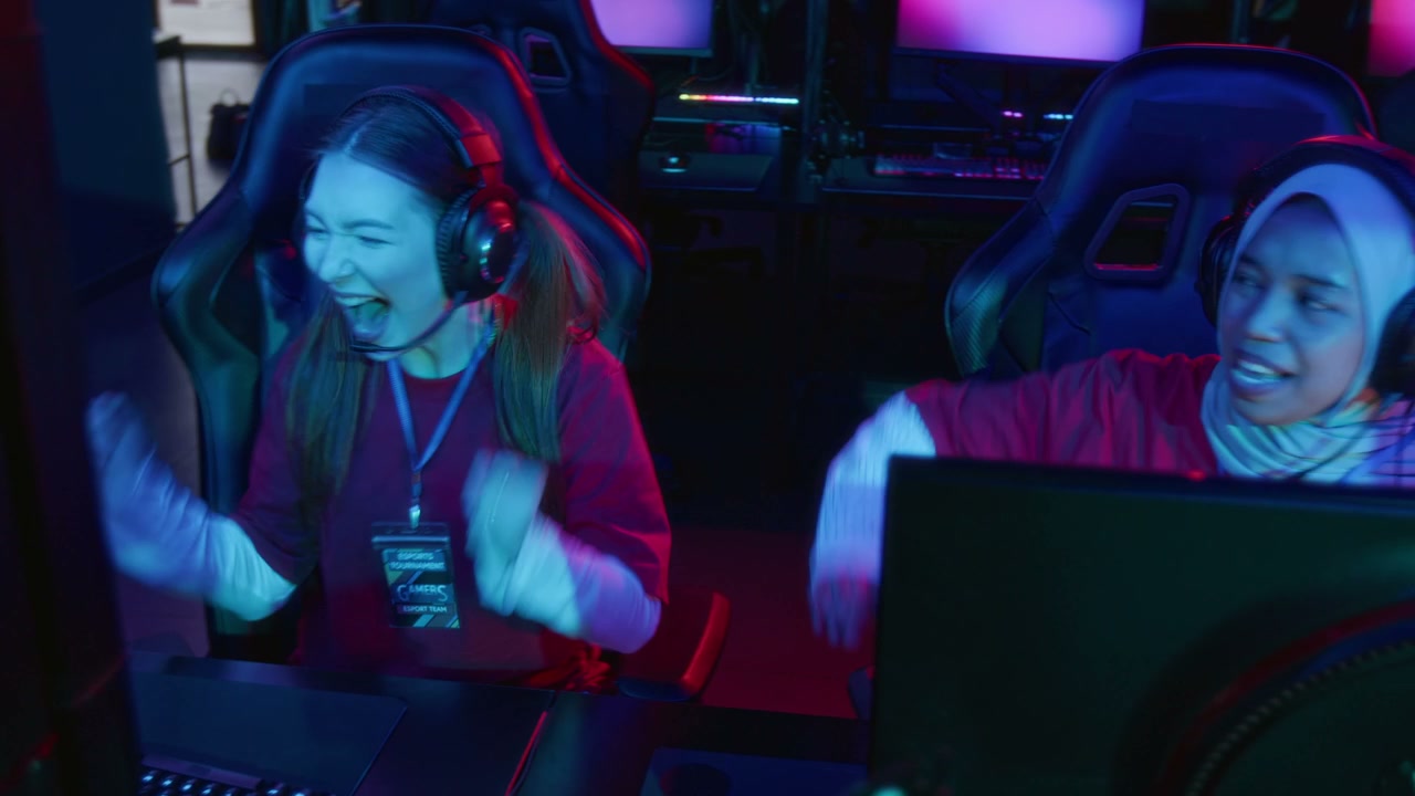 Two Diverse Female Teammates Winning in Multiplayer Video Game with High Fives