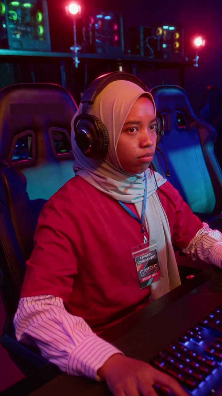 Focused Muslim Girl in Hijab Playing Video Game in Cyberclub