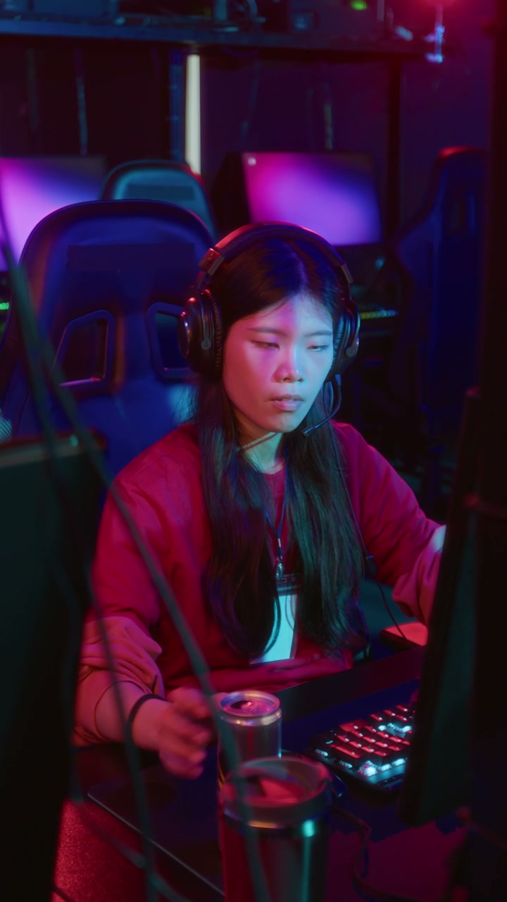 Asian Girl Playing Online Video Game in Cyberclub and Sipping Energy Drink