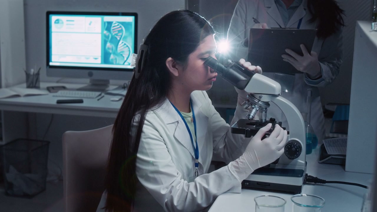 Female Student Using Microscope in Lab
