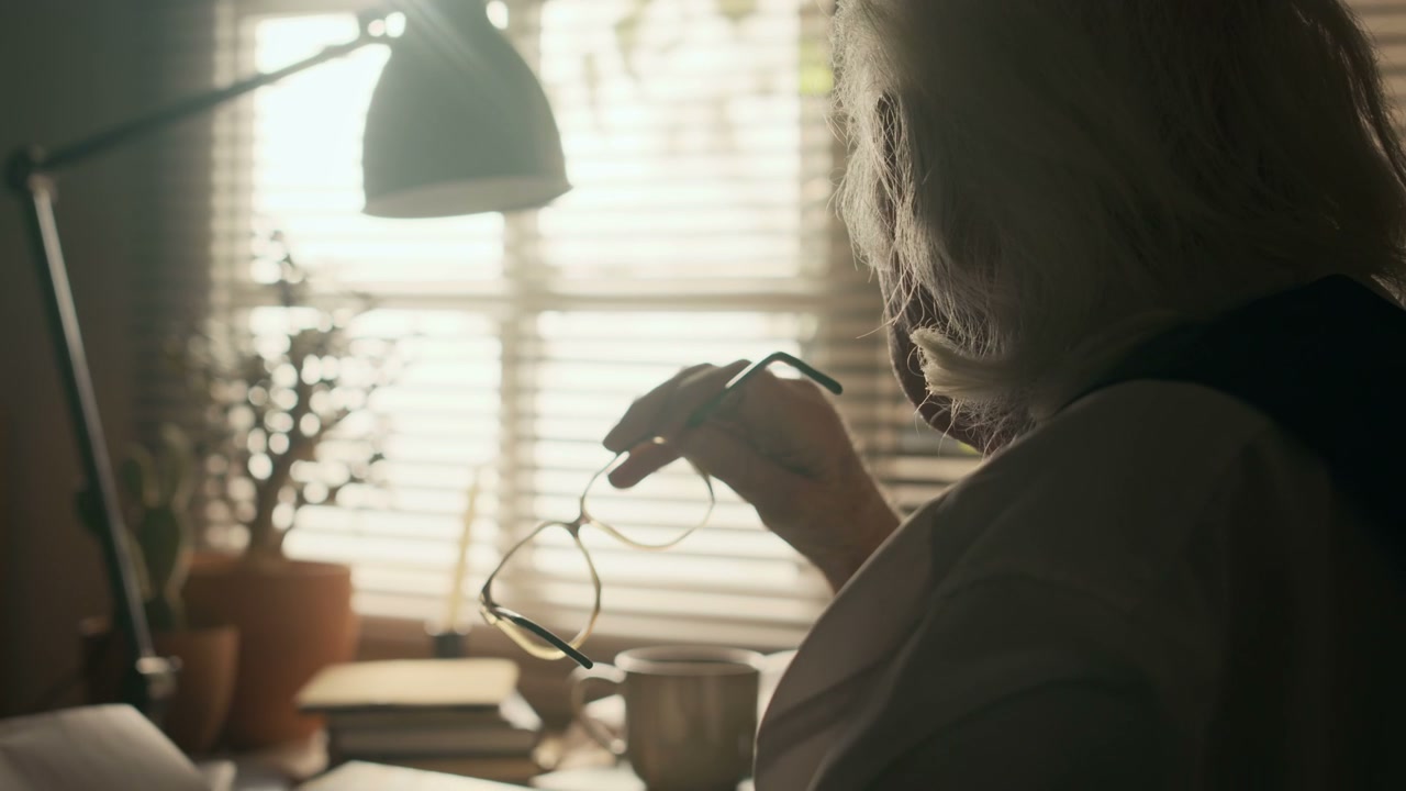 Senior Man Writing at Desk with Typewriter