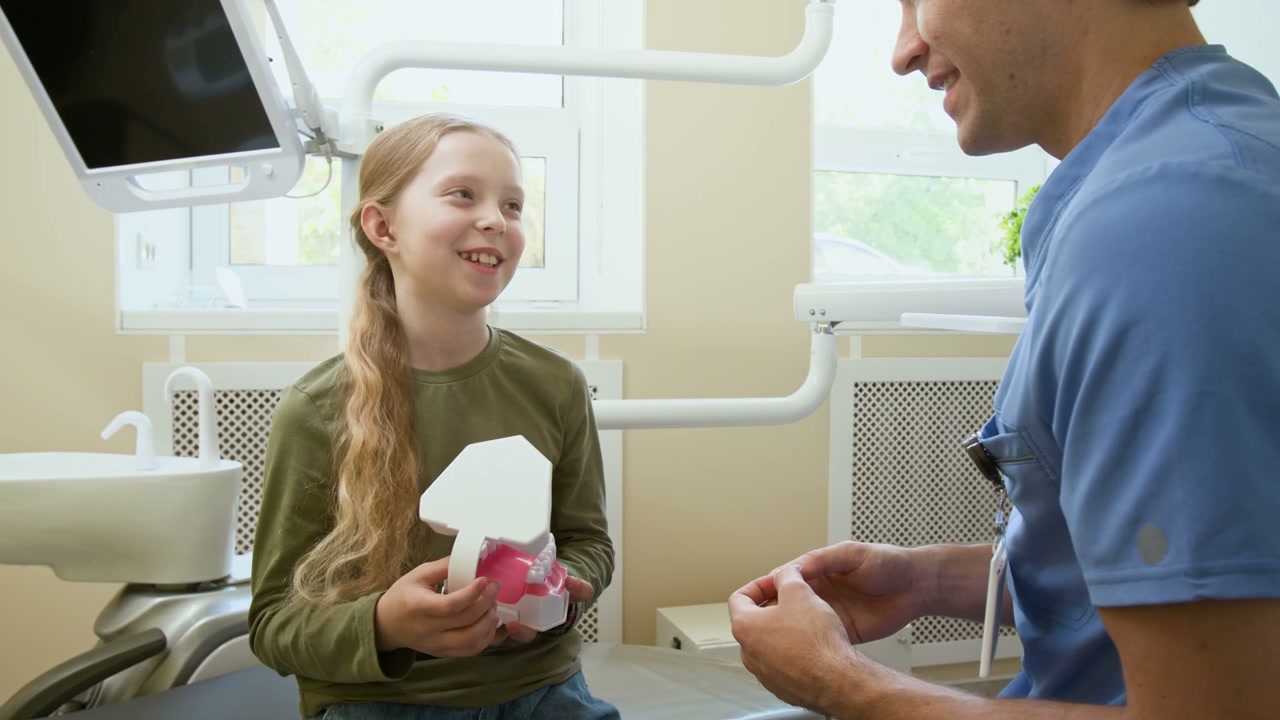 Dentist Explaining Dental Model to Young Girl