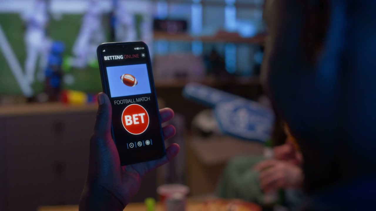 Person Betting on Football Game on Phone