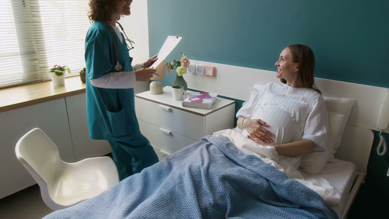 Doctor Talks to Pregnant Woman in Hospital Bed