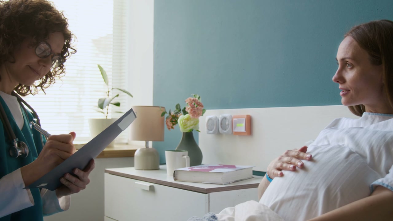 Pregnant Woman Talks with Doctor in Hospital Room