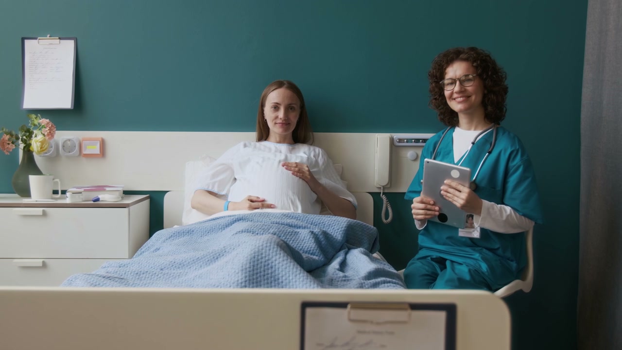 Pregnant Woman and Nurse Smiling in Hospital