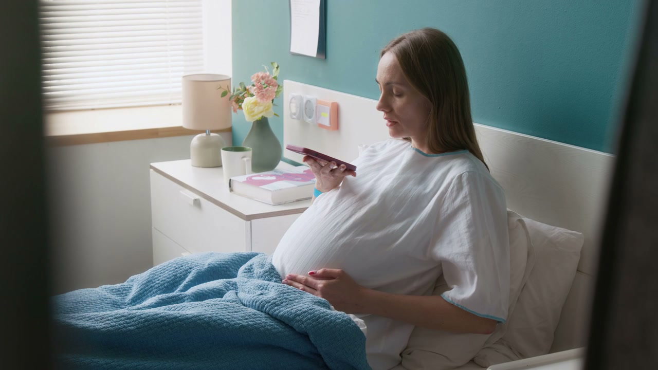 Pregnant Woman Using Smartphone in Hospital Bed