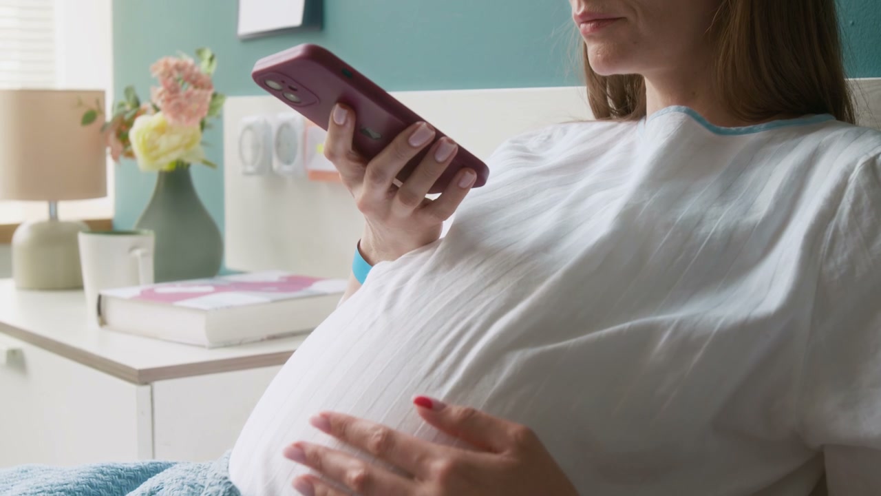 Pregnant Woman Using Phone in Hospital Bed