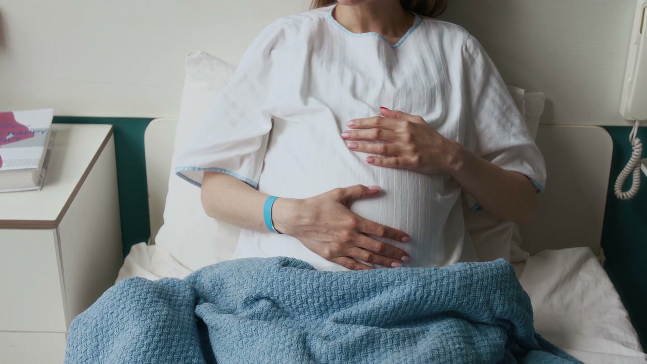 Pregnant Woman Gently Caressing Belly in Hospital