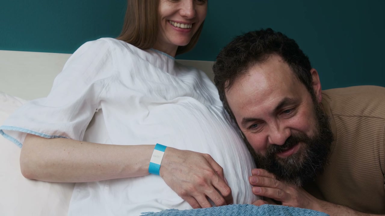 Man Listens to Pregnant Belly in Hospital Room