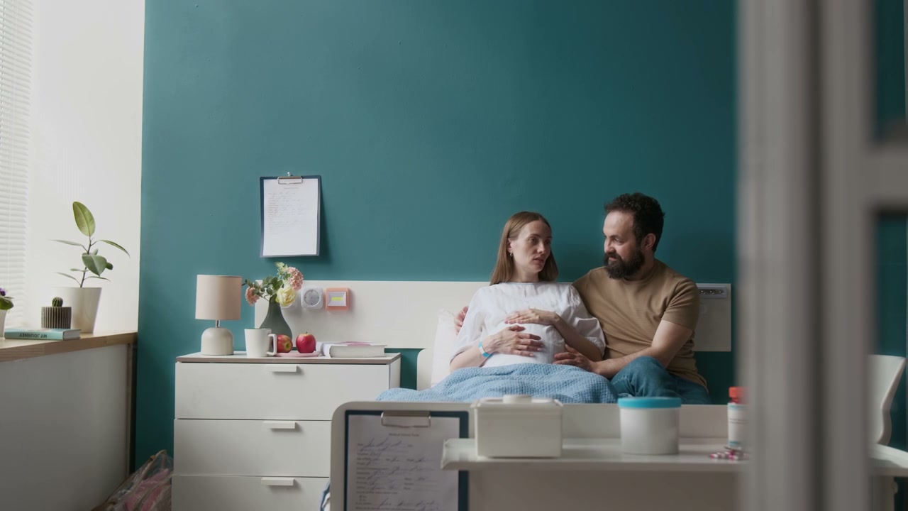 Pregnant Couple Chatting in Hospital Bed