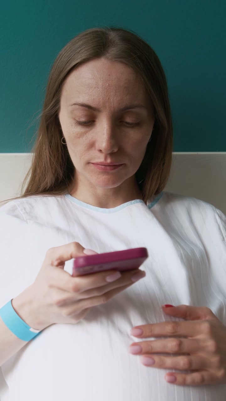 Pregnant Woman Using Smartphone in Hospital Bed