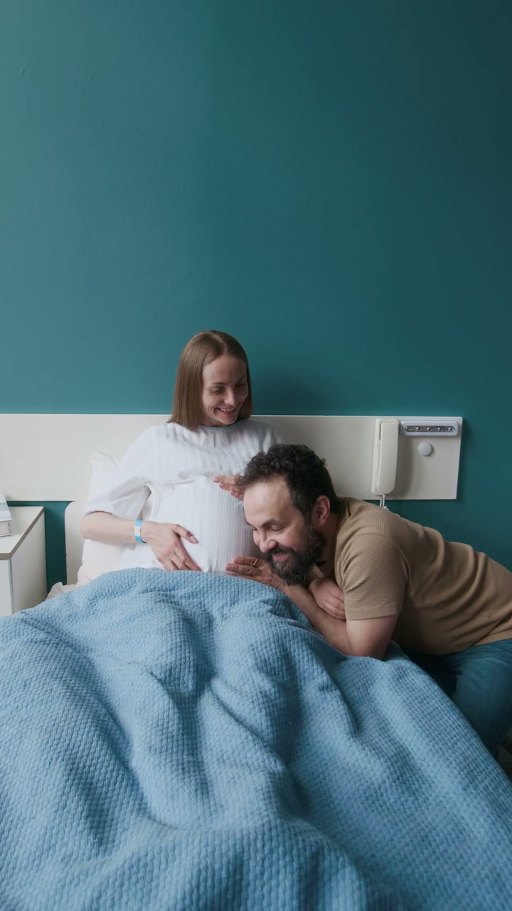 Partner Listens to Pregnant Belly in Hospital Room